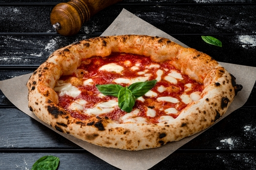 Na imagem há pizza napolitana com molho de tomate, queijo e manjericão