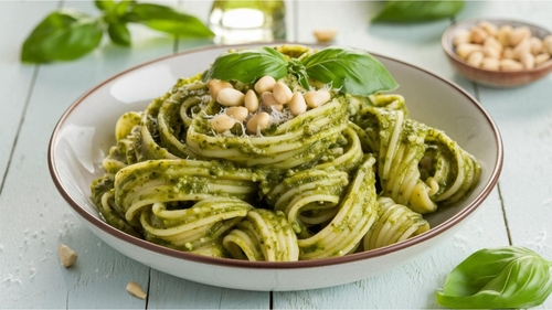 Na imagem, há um prato com macarrão espaguete com molho pesto verde