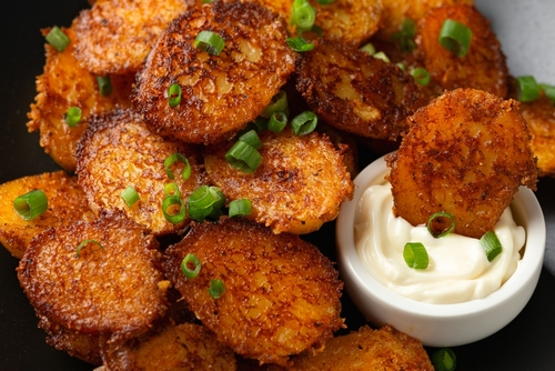 Na imagem, há uma porção de frango empanado com um potinho de molho parmesão